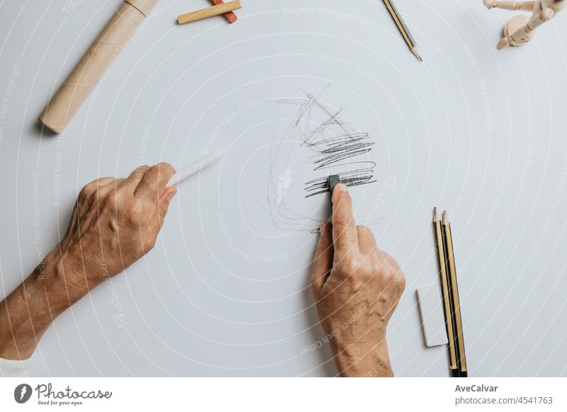 High angle view of a senior Caucasian woman drawing sketches in studio. Creativity, education and people concept,cognitive functions clock drawing self assessment test at home with positive results