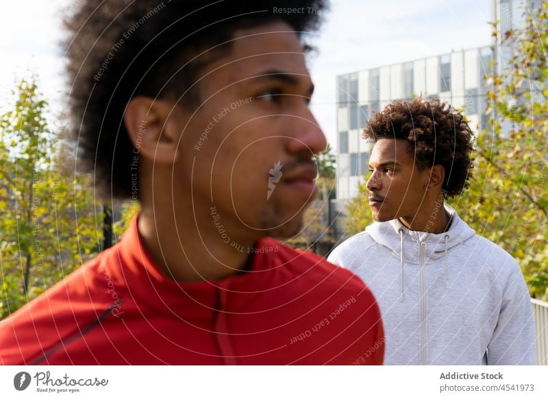 Ethnic males looking away on street men walk urban promenade stroll together direction summer friend casual ethnic gaze curly hair african american black