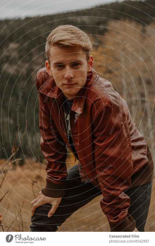 Young man looking directly into camera modeling in the mountains in the fall Aspens Colorado Travel Adventure Wonder Design Fashion Trend Boho Street style