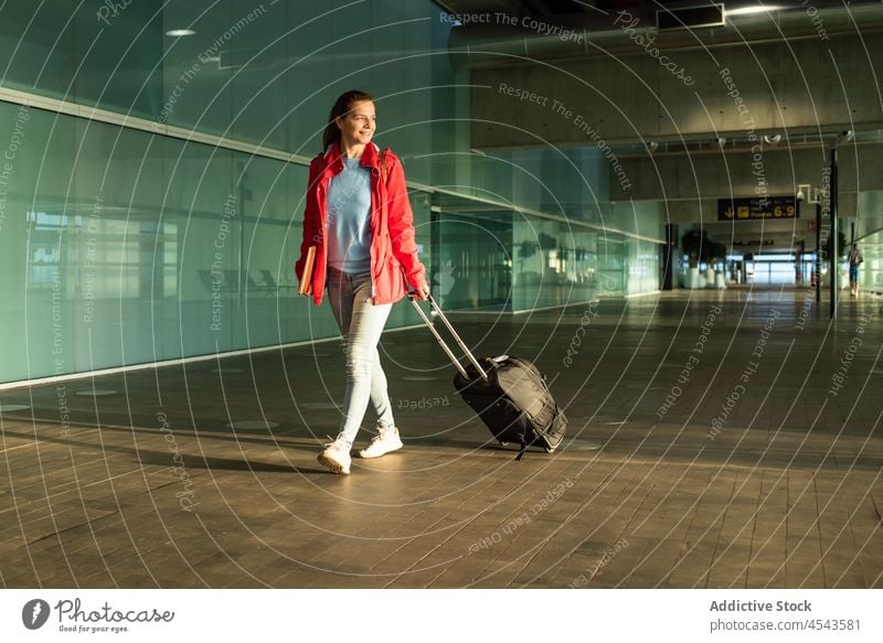 Woman passenger walking with luggage in airport woman suitcase traveler smile trip modern terminal departure lobby public direction contemporary happy tourist