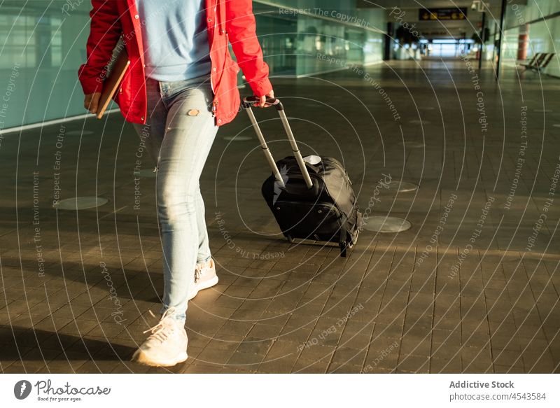 Anonymous passenger walking with luggage in airport suitcase traveler trip modern terminal departure lobby public direction contemporary tourist infrastructure