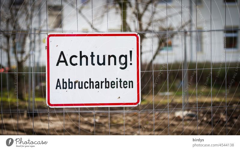 Attention ! Demolition work, sign at a construction fence outline tear off houses condemned Construction site Warning sign Hoarding Signs and labeling