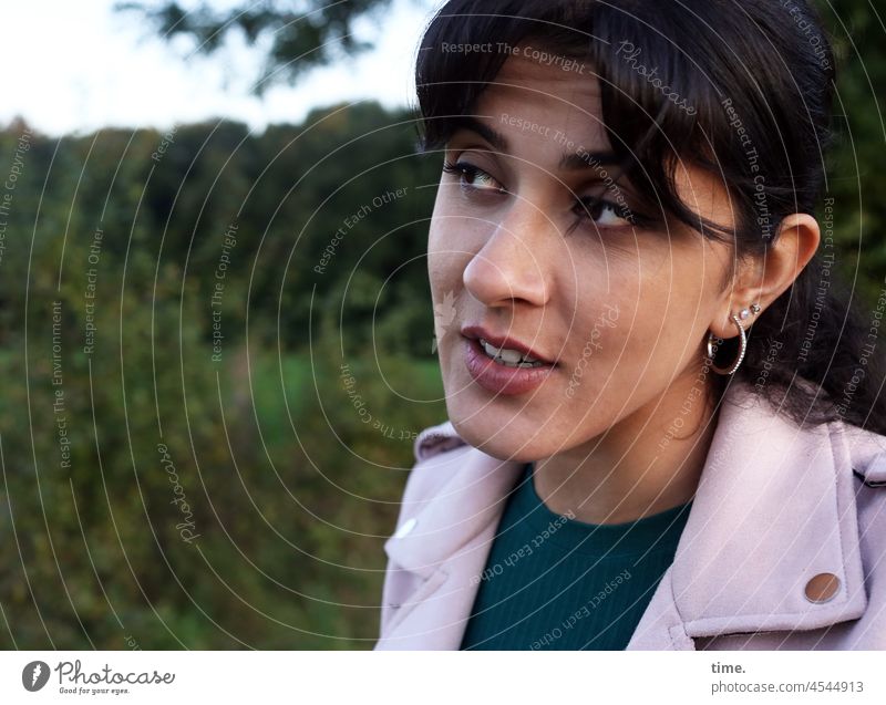 Estila - woman with ear jewellery and sceptical side view in front of a forest edge Curiosity Jewellery Jacket Braids Half-profile Feminine Woman portrait