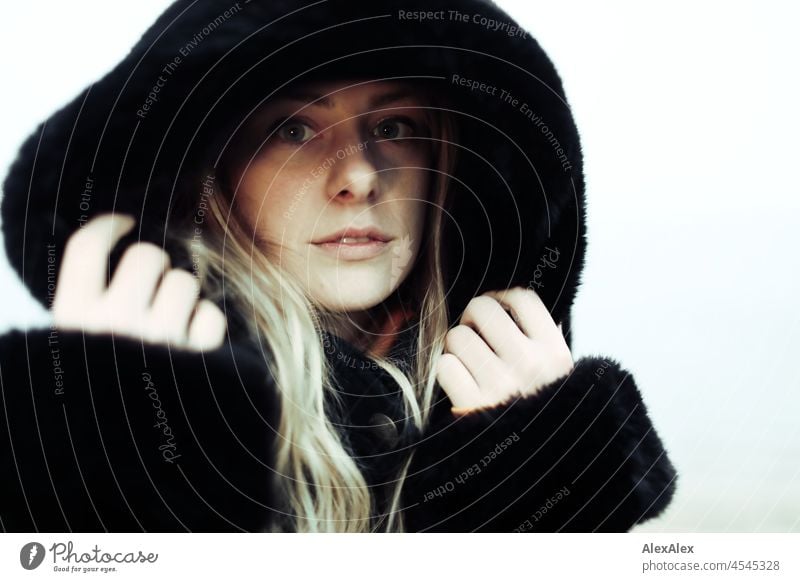 Portrait of a young woman with blond hair standing on a foggy beach in a fur coat with hood Woman Young woman Large Blonde Long-haired pretty daintily Slim