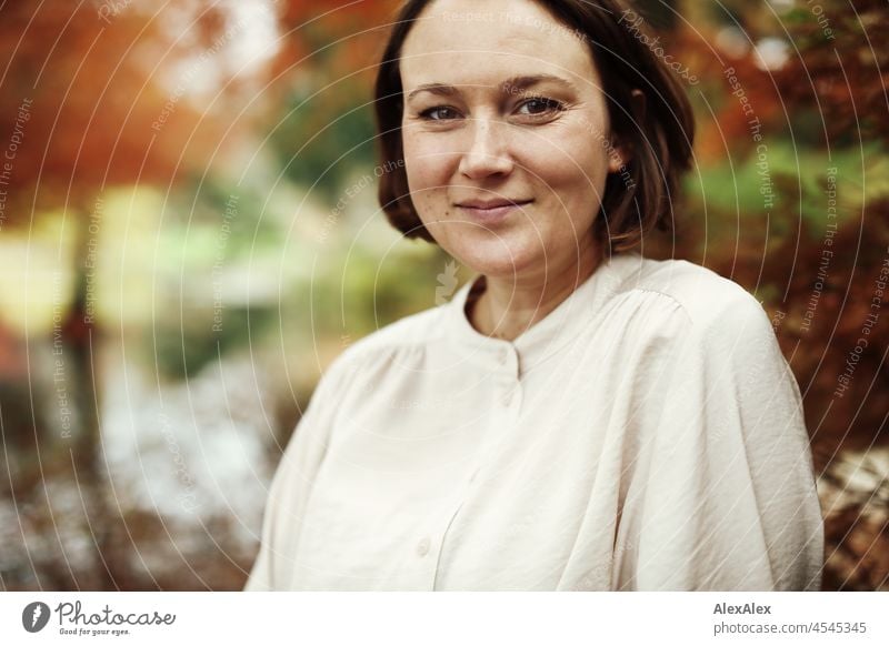 Portrait of a young smiling woman in the park in autumn Cheerful Ease Beige Green Beautiful weather Moody Face of a woman free time Relaxation Self-confident