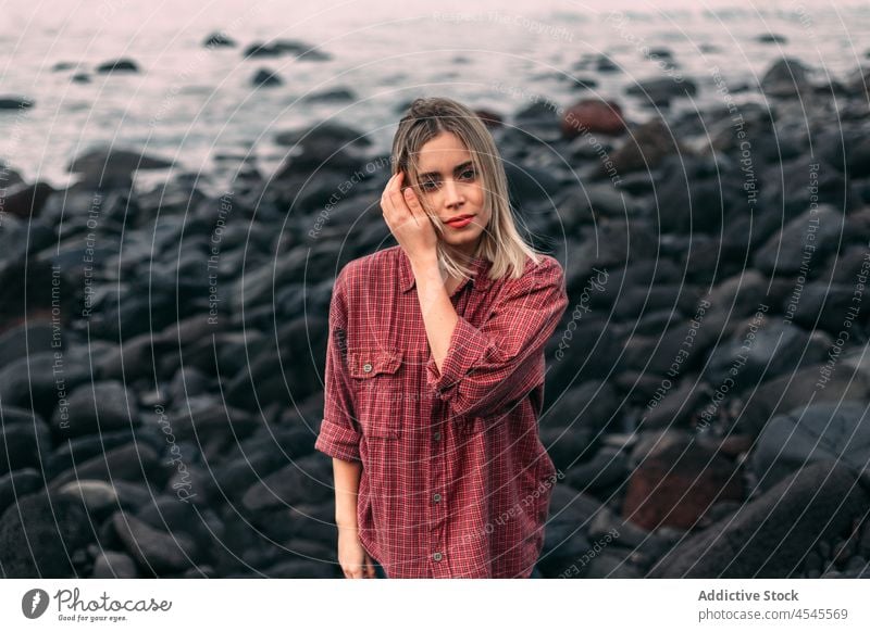 Pensive woman standing on rocky coast with windy weather water sea shore coastal nature flying hair adventure pastime trip stone formation leisure environment