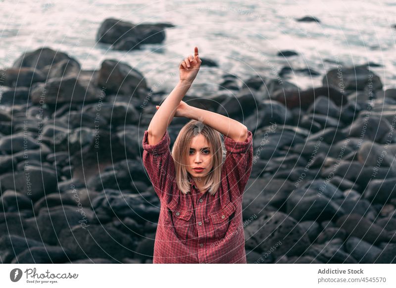 Pensive woman standing on rocky coast with windy weather water sea shore coastal nature adventure pastime trip stone formation leisure environment seaside beach