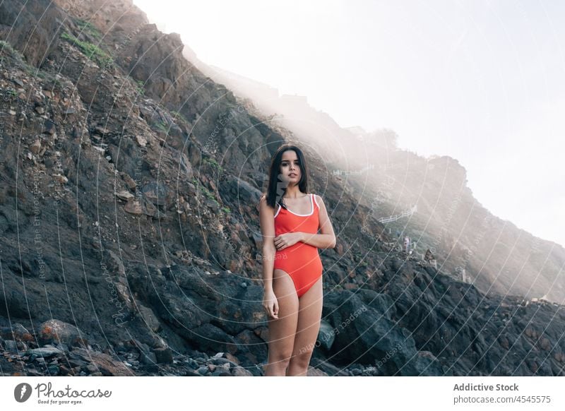 Woman in swimsuit on rocky cliff woman swimwear coast shore coastal nature adventure pastime trip stone formation leisure environment seaside beach seashore