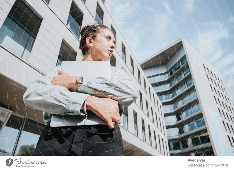 Curly haired african manager business woman while holding her laptop and looking away from camera serious. Attractive young businesswoman wearing white blouse. Copy space working time, finances