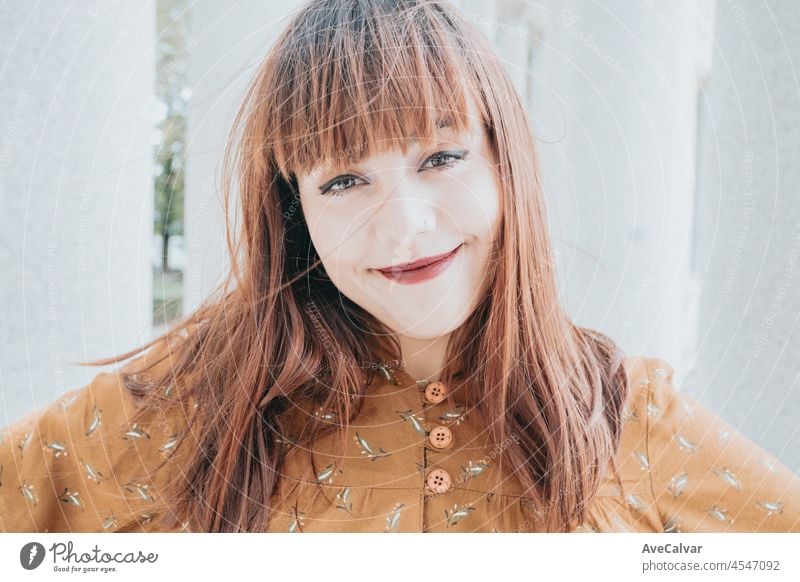 Super smiling close up portrait she her hipster redhead young woman with smart phone. Copy space for text image. Casual dressing in autumnal tones. red lips and modern hairstyle, bright day.