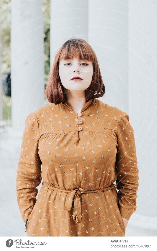 Modern serious pose portrait she her hipster redhead young woman. Copy space for text image. Casual dressing in autumnal tones. red lips and modern hairstyle, bright day. Body Positive