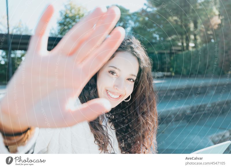 A close-up portrait of an african woman looking into the camera and smiling. The clothing is a classic white sweeter. Student at the university concept, happy learning, sunny day