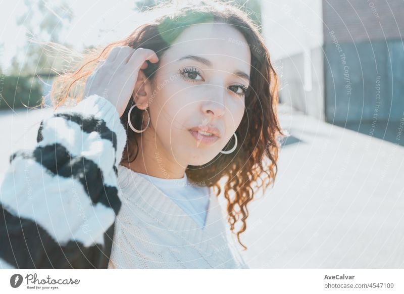 A close-up portrait of an african woman looking into the camera serious. The clothing is a classic white sweeter. Student at the university concept, happy learning, sunny day