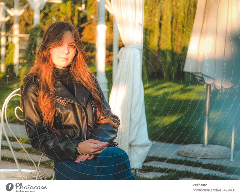 girl wearing blue jeans and leather jacket sit outdoors at sunset woman fashion female casual young white beautiful attractive denim style caucasian background