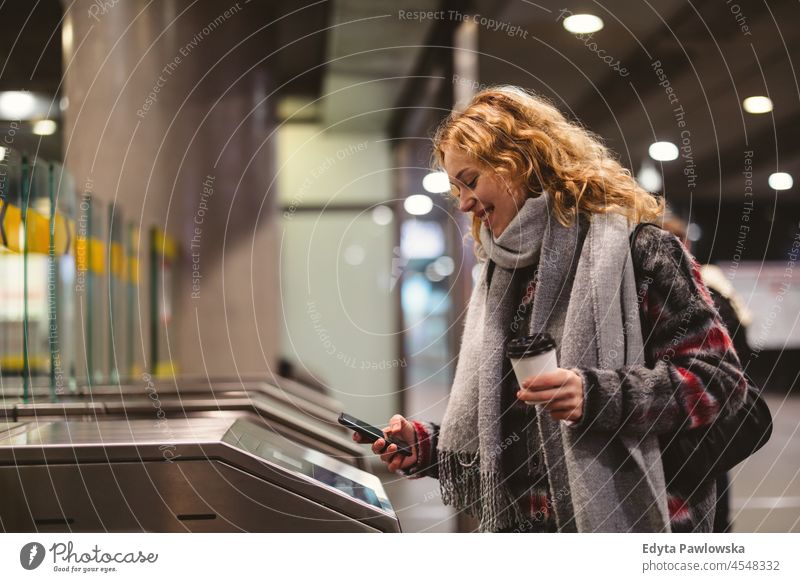 Young woman checking out at metro station using mobile phone one person adult beautiful casual female girl people lifestyle urban city street attractive town