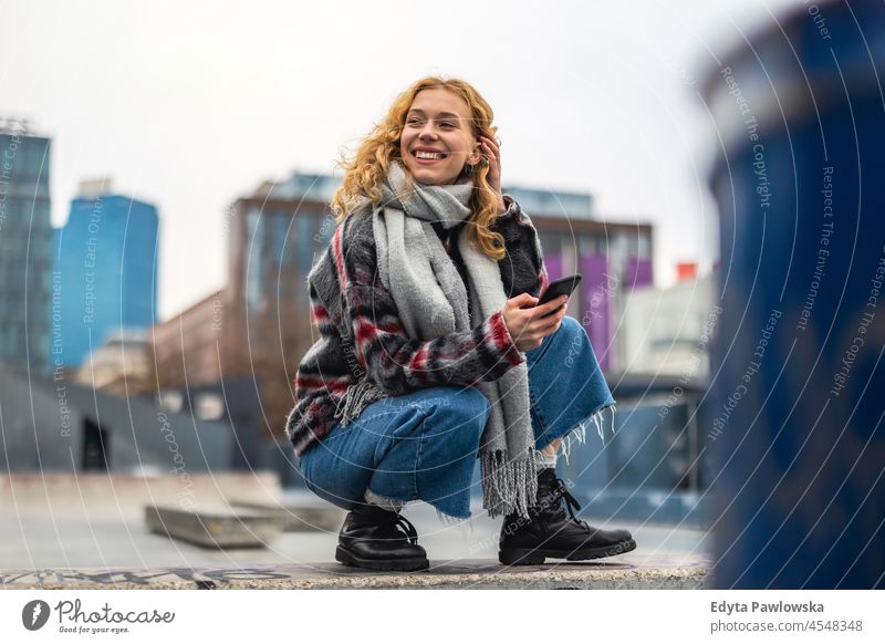 Smiling young woman in the city holding mobile phone one person adult beautiful casual female girl people lifestyle urban street attractive town portrait