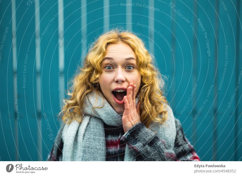 Amazed Young Woman With Mouth Open Against Blue Fence one person adult beautiful casual female girl people lifestyle urban woman city street attractive town