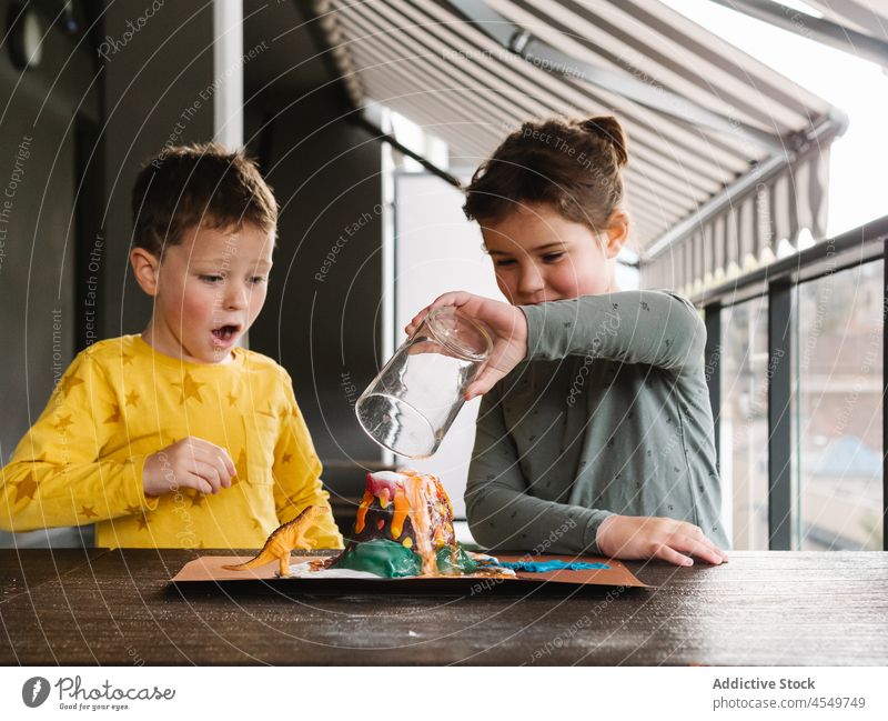 Cute kid pouring water into plasticine volcano crater child liquid girl boy art sculpture mold dinosaur creative adorable colorful childhood casual hobby cute