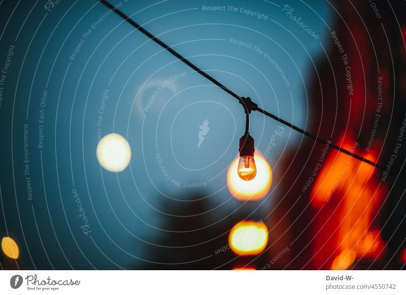 Bulb of a chain of lights at Christmas time is illuminated from behind Fairy lights Christmassy Lighting light source Illusion Dark Light (Natural Phenomenon)