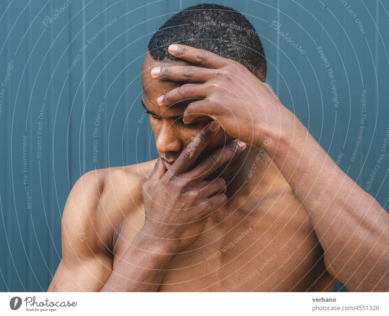 portrait of an young topless athetic african man  on grey background outdoors afro american male expression shirtless hands muscular muscled emotion posing