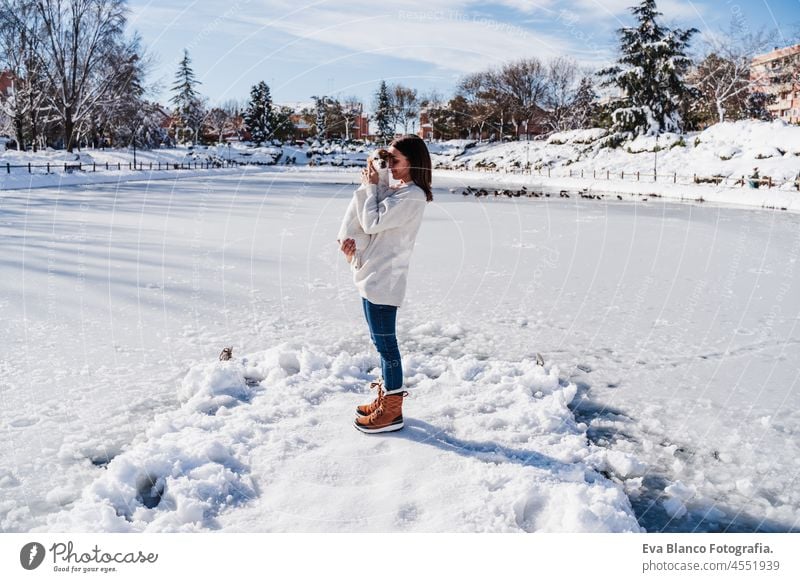 woman hugging cute jack russell dog while standing on snowy pier by frozen lake during winter on sunny day. winter landscape in city park dock cold together