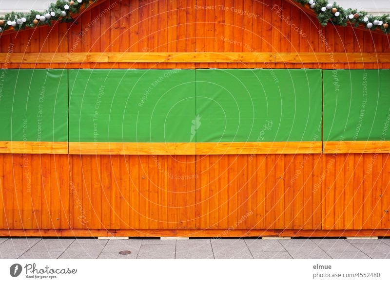 closed wooden christmas stall with green curtain and decorated fir branches on the roof / anticipation / corona ordinance sales booth Christmas booth