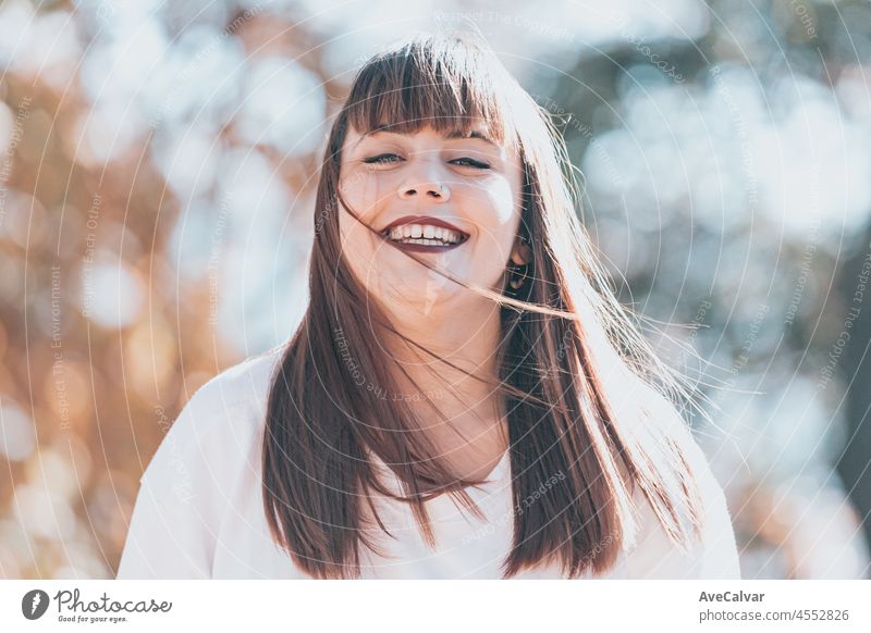 Portrait of redhead young woman walking outside and looking at camera. Happy smiling face. Girl wear white mock up t-shirt. playing with leaf, looking at camera and smiling.