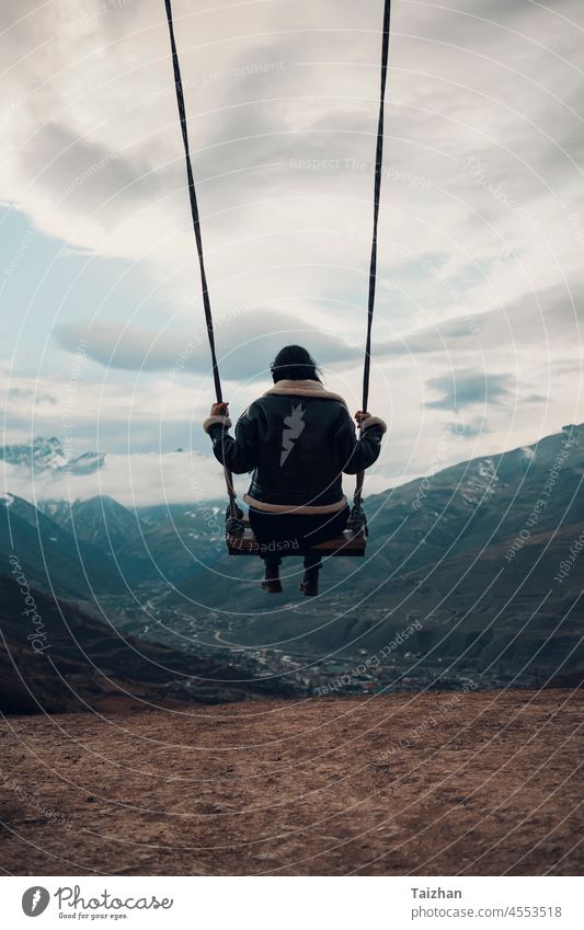 Back view of young woman on swing against mountain landscape Mountains Caucas Ossetia Russia Swing Freedom Dream Dramatic Sky Clouds Fly Flying Rest Relax