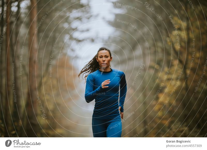 Young woman running toward camera on the forest trail at autumn activity young fit fitness female runner sporty athlete nature woods active lifestyle outdoor