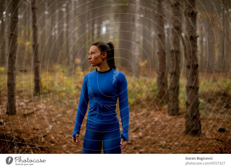 Young woman take a break during outdoor exercise on the forest trail at autumn resting activity adult athlete athletic attractive blue caucasian country