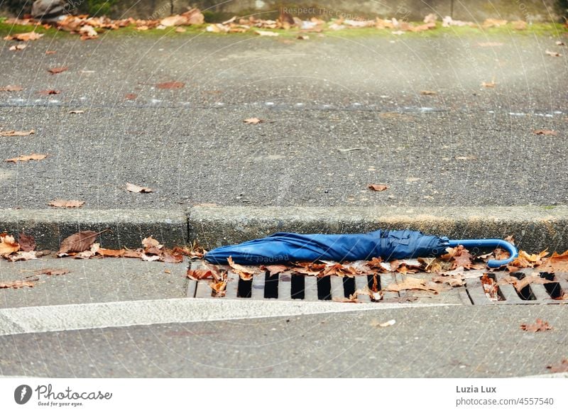 A blue umbrella without a tip was simply dumped at the curb, meanwhile the sun is shining again Umbrellas & Shades Broken Doomed Disposed of jettisoned