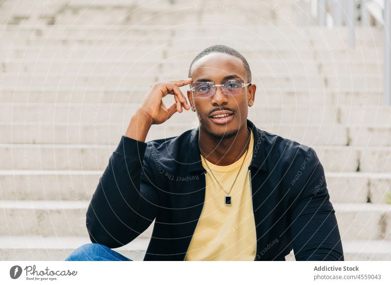 Happy ethnic male sitting on street stairs man portrait staircase rest cheerful positive smile step ladder optimist eyeglasses content enjoy chill delight happy