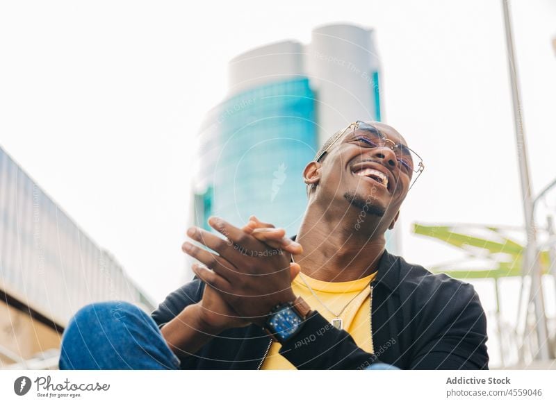 Happy ethnic male sitting on street stairs man portrait staircase rest cheerful positive smile step laugh ladder optimist eyeglasses content enjoy chill delight