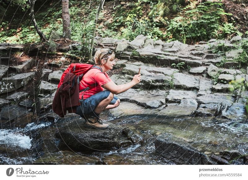 Taking pictures from vacation. Woman with backpack taking photos of landscape using smartphone camera summer trip mountain travel journey adventure hiking