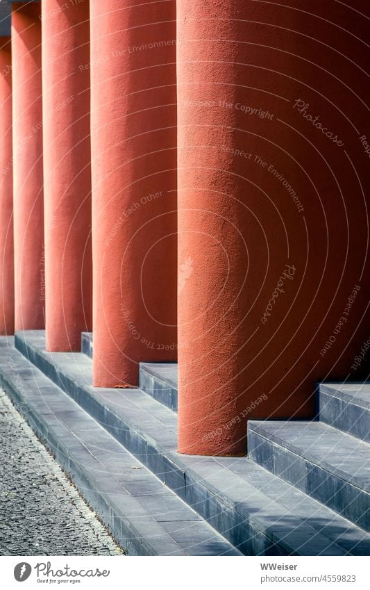 Thick orange-red columns support the canopy of the building, with steps in between. Abstract Orange Red Column geometric urban Architecture Design Facade