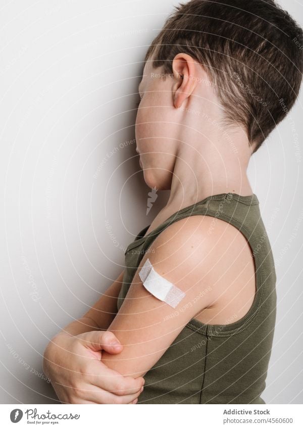 Schoolboy after vaccination with band aid on arm child vaccine cheerful jab serious kid shot injection healthy motivation childhood support medical epidemic