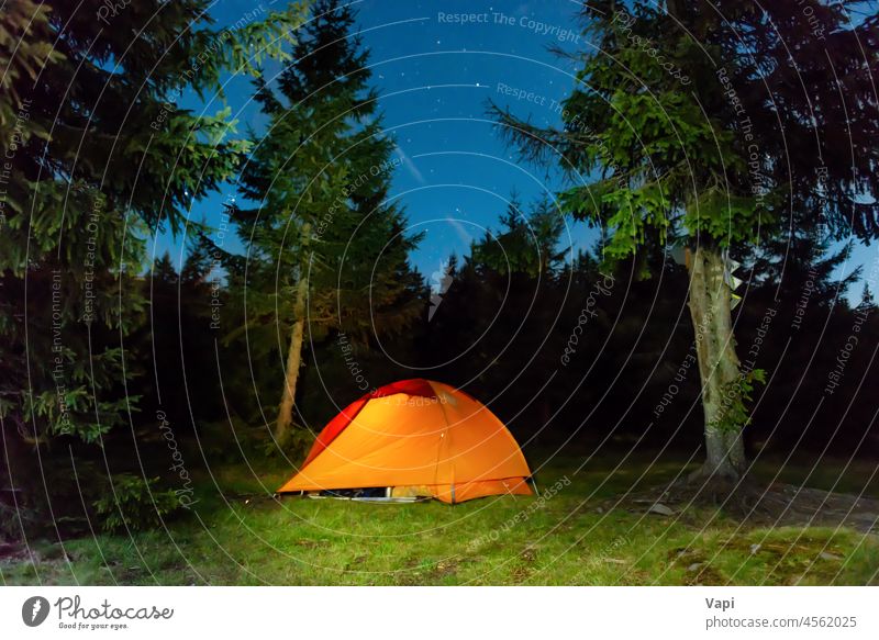 Illuminated tent in night forest mountains illuminated stars nature landscape red orange yellow outdoor light travel sky tree grass pine summer hiking camp