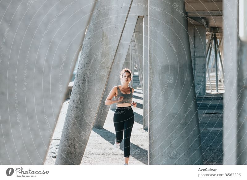 Portrait of a running serious young african arab woman smiling after jogging at outdoors. Straight to camera, fitness body type. Urban exercise outdoors. person