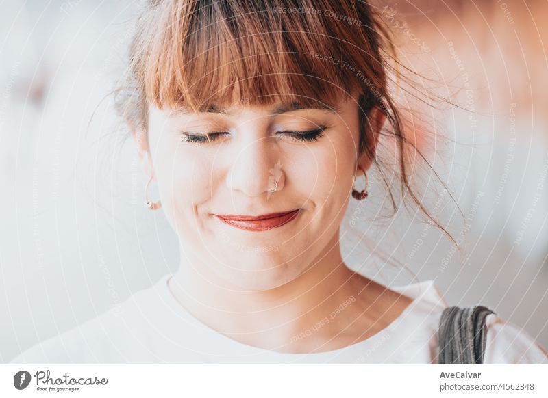 Close up portrait Young red head laughing to camera hipster woman .Trendy girl in summer T-shirt and black jeans .Happy and positive female posing in the street near a brick wall.