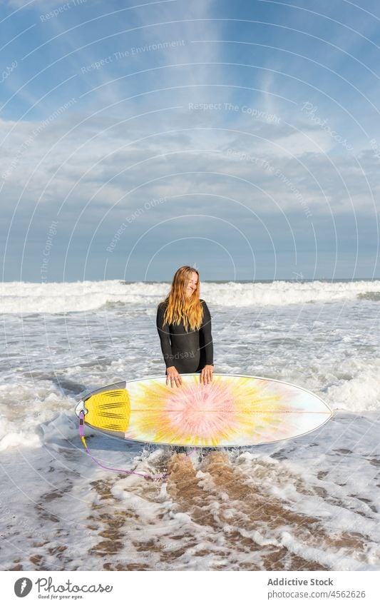 Woman with surfboard standing on wet beach woman coast shore smile hobby activity pastime sport sea water tide wave waterfront seaside nature seashore equipment