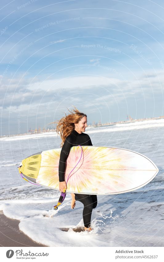 Woman with surfboard walking on wet beach woman coast shore hobby activity pastime sport sea water tide wave waterfront seaside nature seashore equipment summer