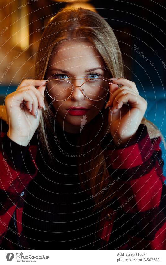 Young woman sitting on a coffee shop young portrait blonde calm casual caucasian clothes colorful confident cute enjoy female attractive glasses hipster indoors