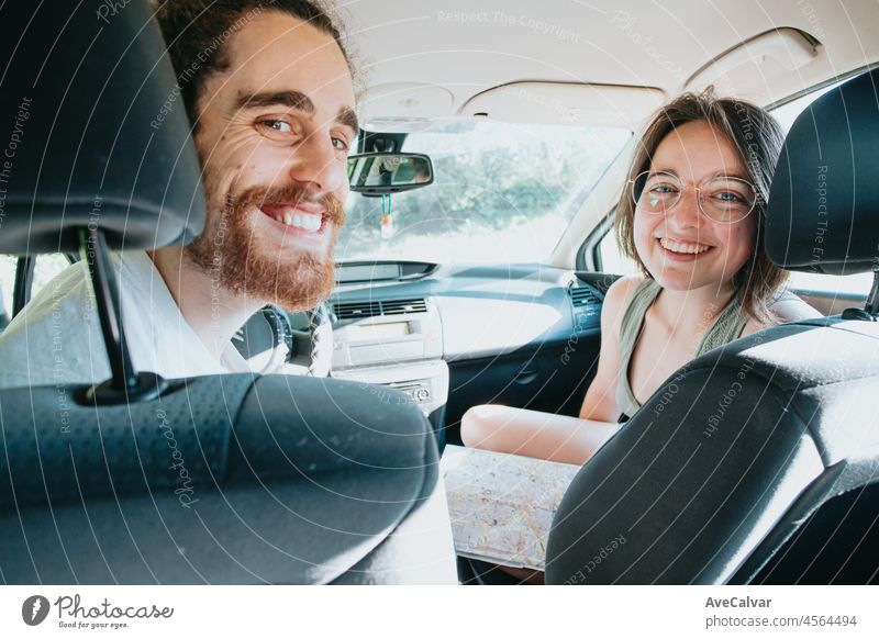 Young hipster couple using a map on a road trip for directions. Reading a map. Cheerful loving couple relaxing on vacation. Trip on route vacation. Happy and smiling to camera. Decision taking