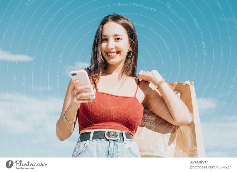 Young african woman with shopping bags using smart phone and shopping at mall, Woman lifestyle concept. Making a call and sending messages during shopping rest