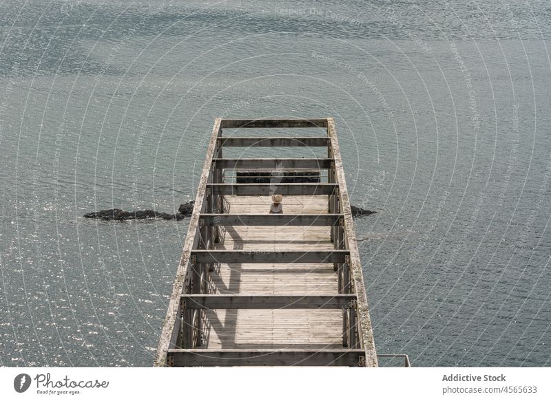 Woman sitting on pier against calm sea woman tourist travel observe wooden seascape boardwalk fence construction railing cargadero da insua spain female galicia