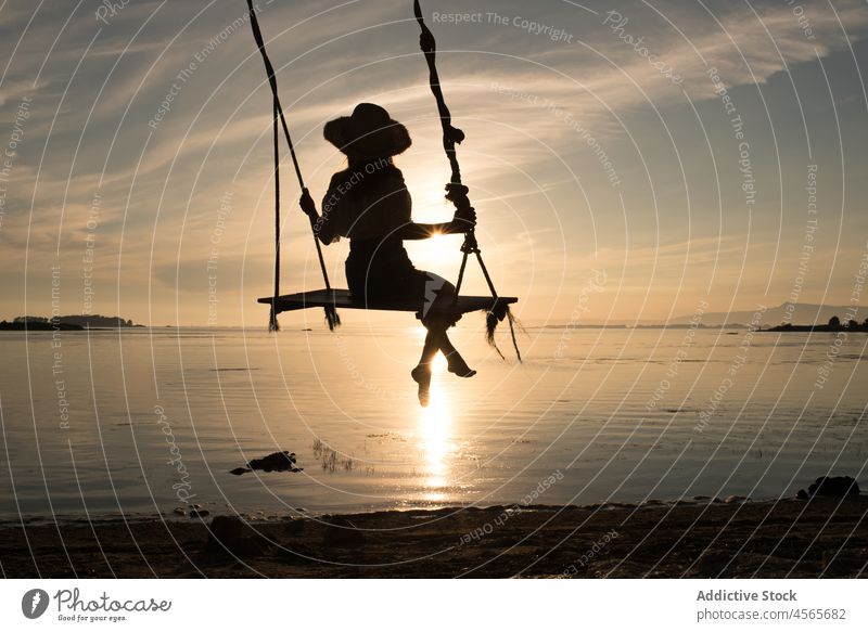 Unrecognizable woman sitting on swing over sea at sunset silhouette sundown spain cambados evening sky dusk nature enjoy relax rest twilight harmony summer