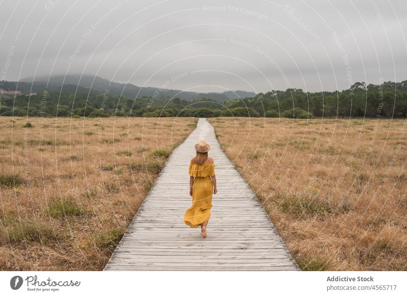 Woman walking on boardwalk in countryside woman dune footpath nature meadow grass corrubedo galicia female barefoot spain wooden field summer dress rural