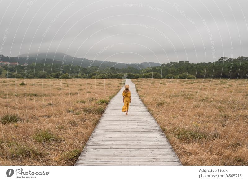 Woman walking on boardwalk in countryside woman dune footpath nature meadow grass corrubedo galicia female barefoot spain wooden field summer dress rural