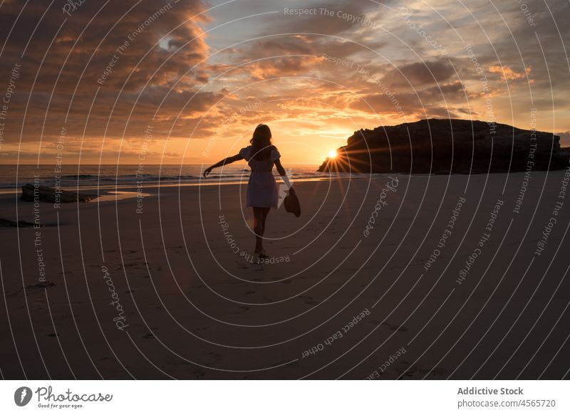 Anonymous woman standing on beach against sundown silhouette sunset sea shore twilight cliff picturesque beach of the cathedrals galicia walk spain enjoy female