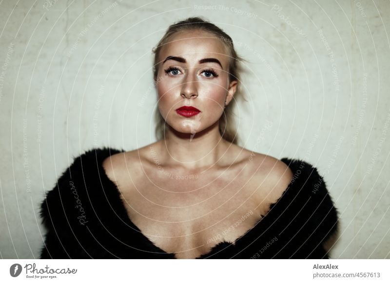 Portrait of a young blond woman with chin dimples - she wears only a black coat very wide open and stands in front of a concrete wall Woman Young woman pretty